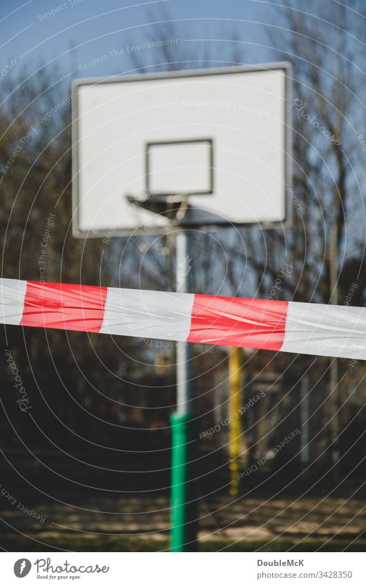 Playing prohibited - Basketball court closed due to coronavirus cordon barrier tape blocking Basketball arena Basketball basket Day Exterior shot Colour photo