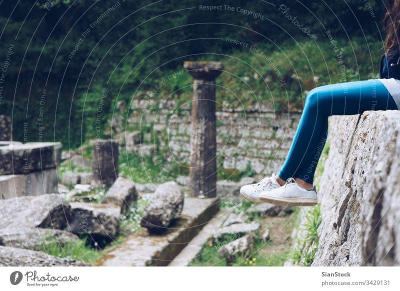 Girl is sitting on remains of a Doric temple, Mon Repos park, Corfu Town, Greece corfu mon greece palace repo repos kerkira island building landmark historic