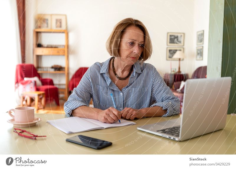 Middle age senior woman working at home using computer female laptop mature people one house person lifestyle desk drink glasses attractive relax technology job