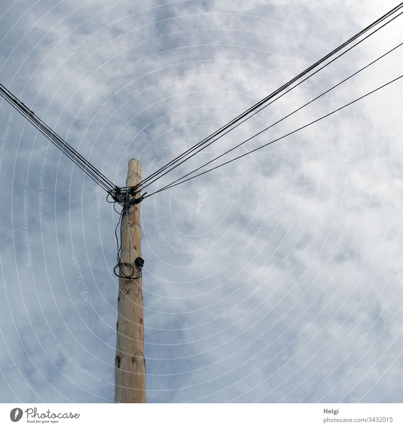 high wooden mast with many attached power lines in front of a cloudy sky Pole Electricity pylon Cable Energy industry electricity Transmission lines Technology