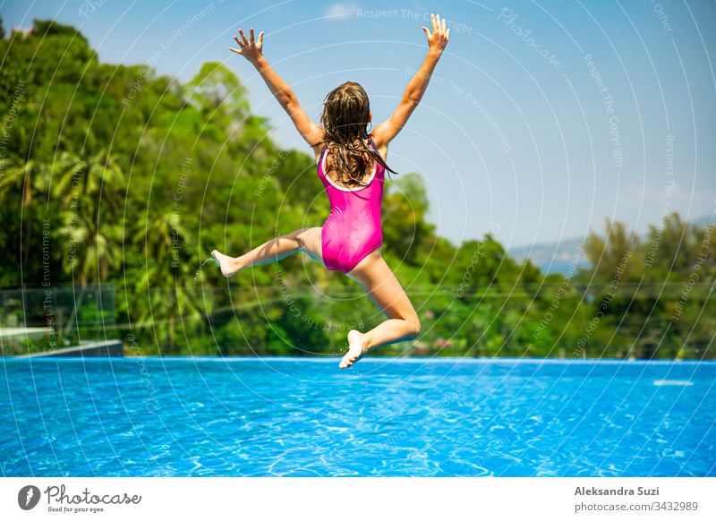 Excited funny little girl jumping to the swimming pool. Happy summer vacation active adventure asia blue candid carefree cheerful child childhood colorful crazy