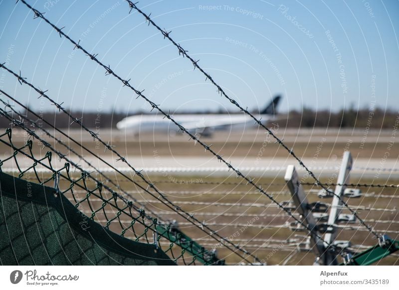 spiked fence with a blurred plane parked behind it Airplane Barbed wire fence Fence Exterior shot Airport Safety Border Barrier Deserted Colour photo Protection