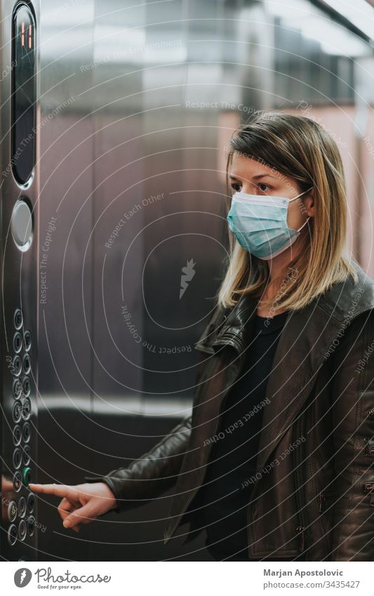 Young woman with medical mask in the elevator of an apartment building adult biohazard care caucasian coronavirus covid19 crises danger disease disposable