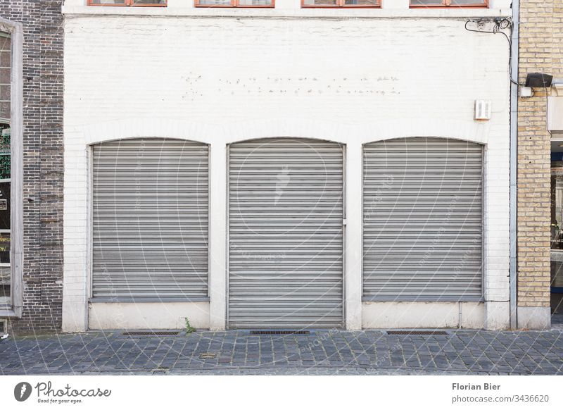 Closed shop with lowered shutters in an ancient façade business Store premises roller shutter Crisis Window Door Retail sector Facade Cobblestones brick