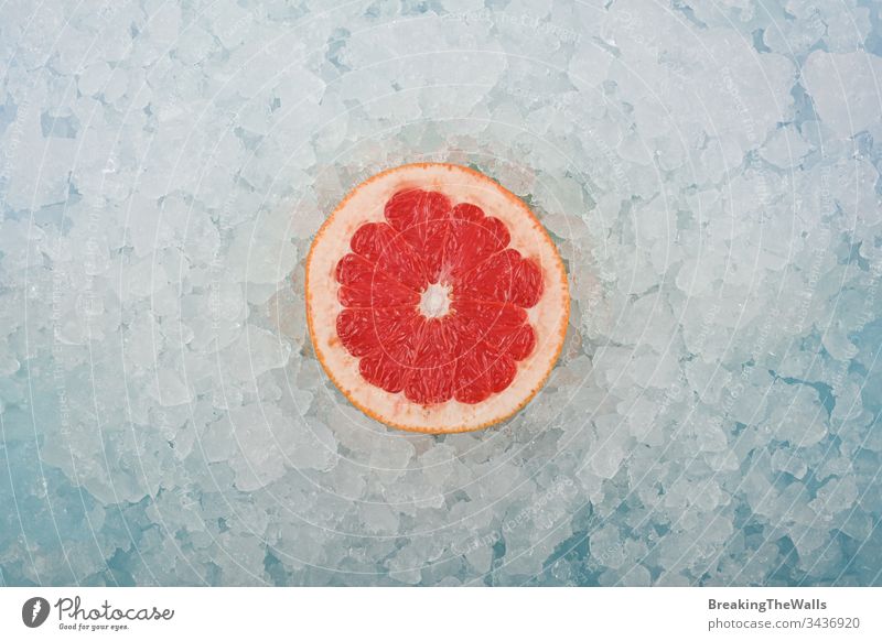 Fresh pink grapefruit slice over crushed ice Grapefruit red one half cut fresh background closeup blue white cold frozen vitamin healthy eating cooking