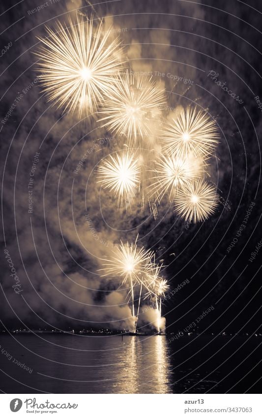 Luxury fireworks event sky water sea show with yellow stars. Premium entertainment magic star firework at e.g. New Years Eve or Independence Day party celebration. Nice lake surface reflections