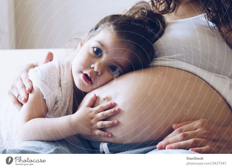 Happy kid girl hugging pregnant mother's belly child woman pregnancy mom family white baby happy little love lying young bed bedroom maternity beautiful waiting