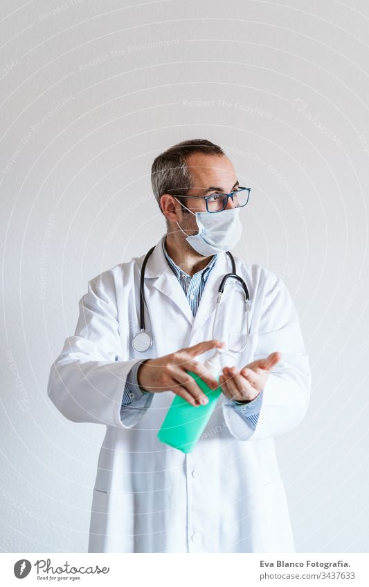 doctor man wearing protective mask indoors. Holding an alcohol gel or antibacterial disinfectant. Hygiene and corona virus concept. Covid-19 professional