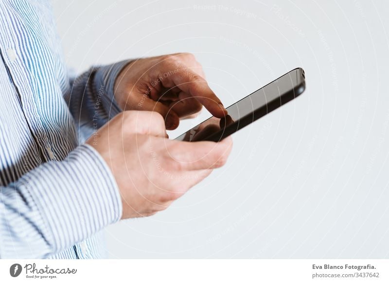 close up view of a man using mobile phone indoors. Technology concept unrecognizable technology wireless shirt working internet texting finger executive