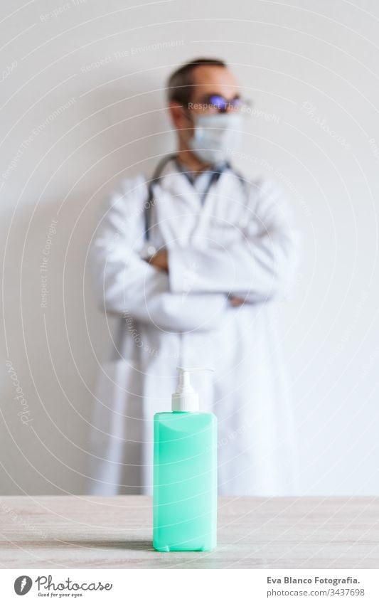 doctor man wearing protective mask and gloves indoors. Holding an alcohol gel or antibacterial disinfectant. Hygiene and corona virus concept. Covid-19