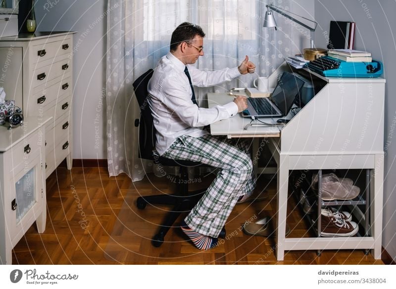 Man teleworking wearing shirt, tie and pajama pants working from home video call agreement coronavirus epidemic quarantine telecommuting covid-19 business