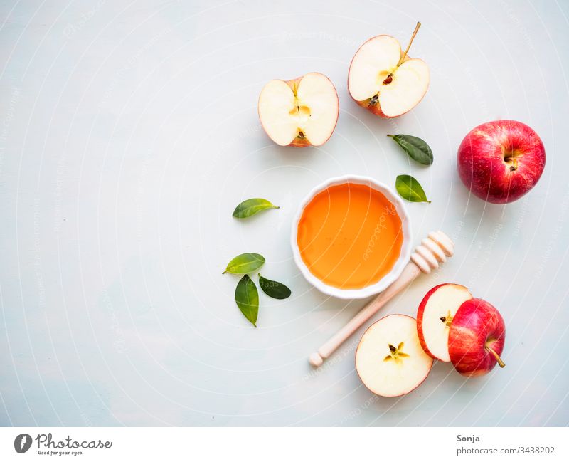 Roter halbierter Apfel und eine weiße Schüssel mit Honig auf einem hellen Hintergrund, Flat lay, gesunde Ernährung apfel rot honig honiglöffel draufsicht Fruit