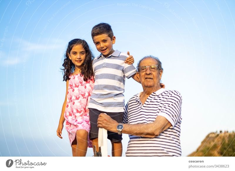 Grandfather and grandchildren against blue sky. Summer time. adult age aged beach boy carefree caucasian cheerful childhood family fathers day fun generation