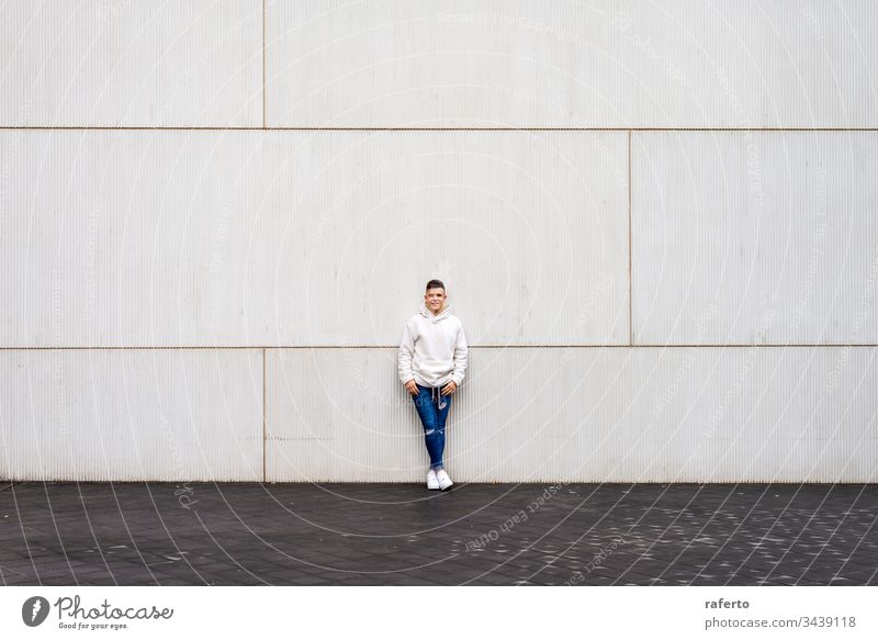 Portrait of young male with hands on pocket leaning on wall outside outdoors man portrait grey smiling happy 20s horizontal adult confident copy space content