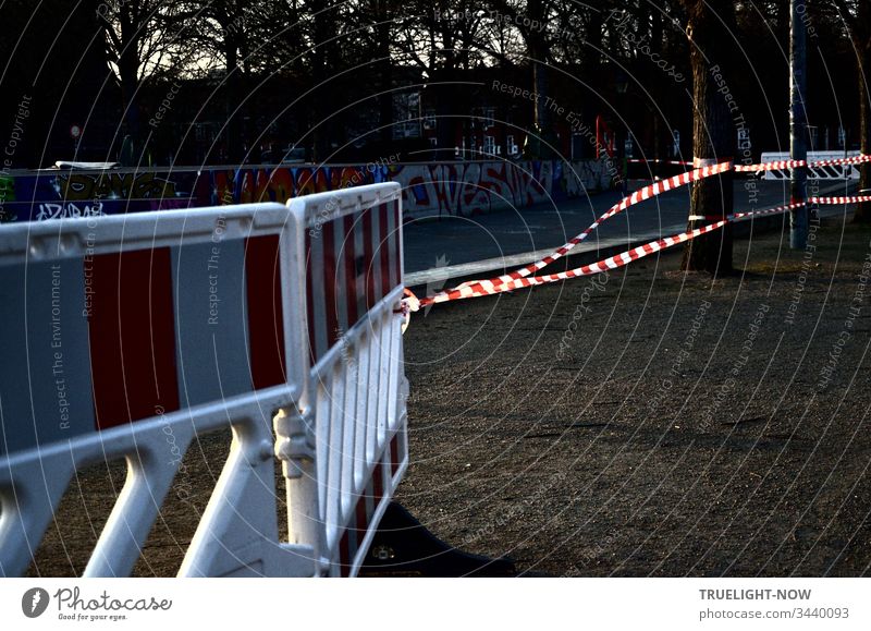 Corona Thoughts | Fenced off green area with red and white barrier grid and red and white barrier tape that flutters in the evening wind pandemic Fear crowbar