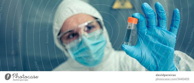 Scientist with protection suit looking vial in the laboratory scientist examining flask vaccine virus coronavirus investigation banner web header panorama