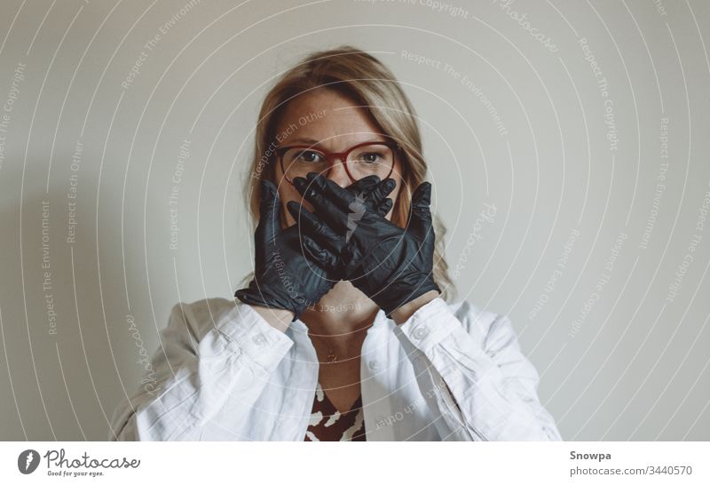 Woman Covering her Face with Black Gloves on glove black gloves rubber glove Doctor Scientist Blonde blond hair scrub covid-19 coronavirus Virus Stop attention