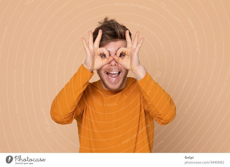Attractive young guy yellow orange look out keep a watch on see observe eyes watchman gossiping glasses vision scoffing make fun happy adult twenty male model