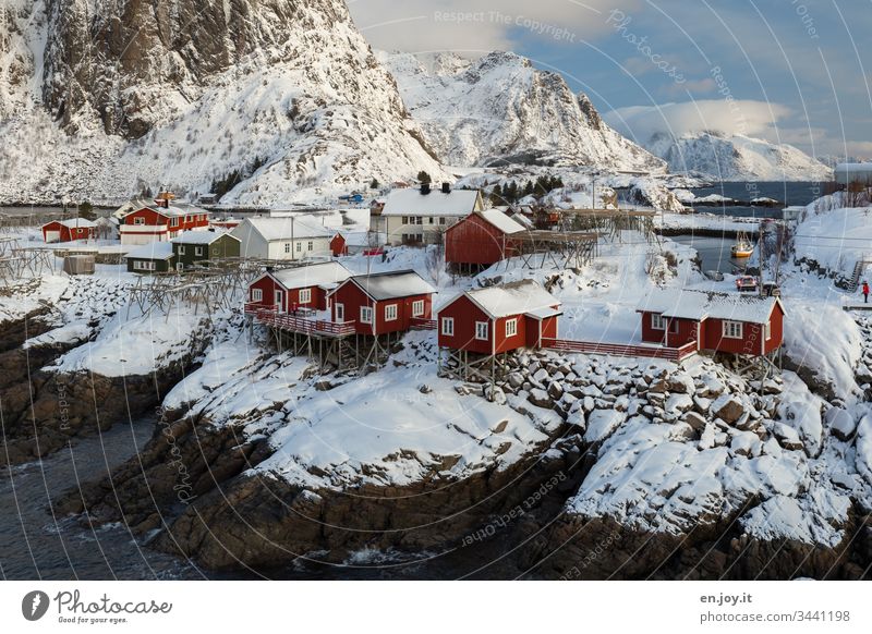 Hamnoy on the Lofoten with a view of the small red houses standing on snowy rocks Panorama (View) Reinefjorden Fjord Coast cloudy Light and shadow