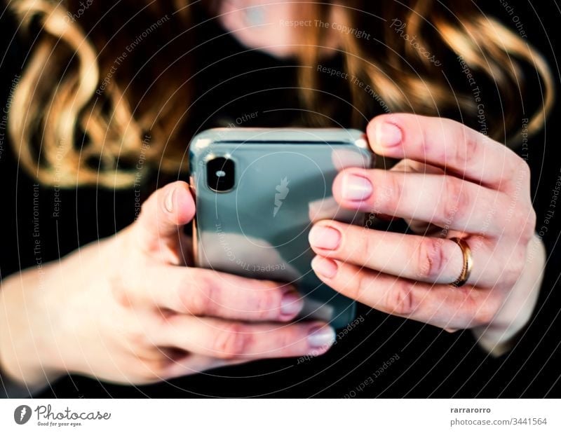 the hands of a young caucasian brunette woman while holding a smartphone typing on the touch screen. Women Mobile Phone Holding People Technology Females