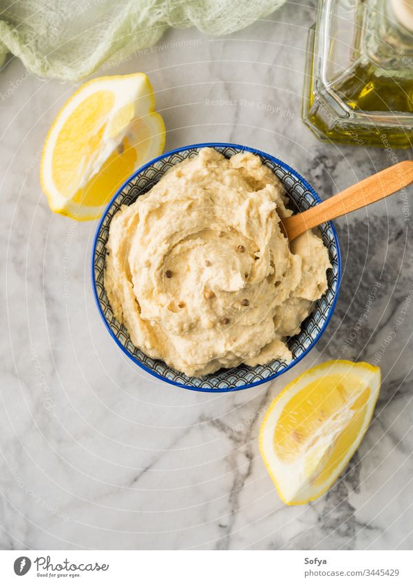 Mashed chickpeas Hummus dip in bowl hummus mashed tahini oriental vegan vegetarian healthy oil lemon garlic cumin blend sauce marble board cook spice