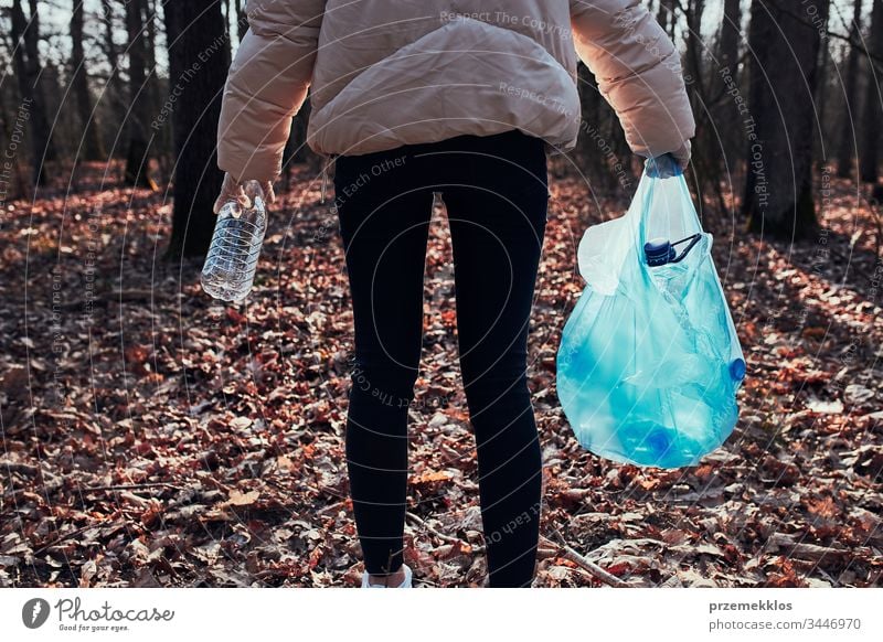 Young woman cleaning up a forest. Volunteer picking plastic waste to bags. Concept of plastic pollution and too many plastic waste. Environmental issue. Environmental damage. Responsibility for environment. Real people, authentic situations