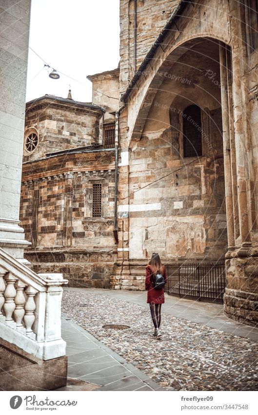 Young woman walking by Bologna Centre architecture backpack belltower bologna bologne bright building city clock coat day distance europe facade from italian