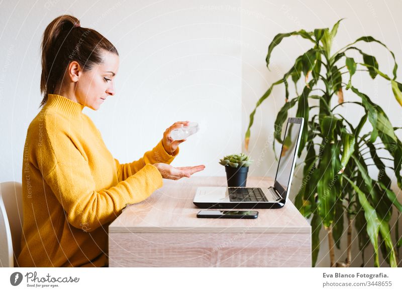 young woman working on laptop at home, using hand sanitizer alcohol gel. Stay home during coronavirus covid-2019 concept disinfectant hands antibacterial