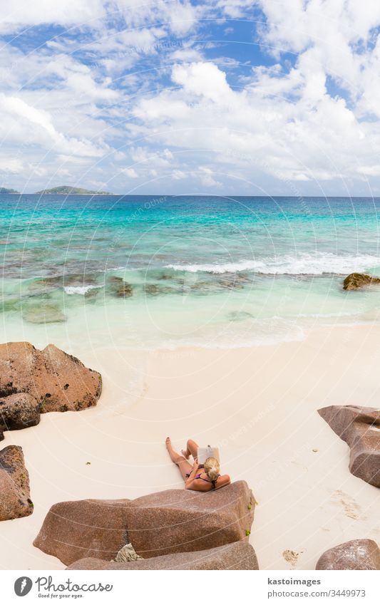 Woman reading book on picture perfect beach Anse Patates on La Digue Island, Seychelles. travel summer vacation woman seychelles lifestyle holiday sea sand