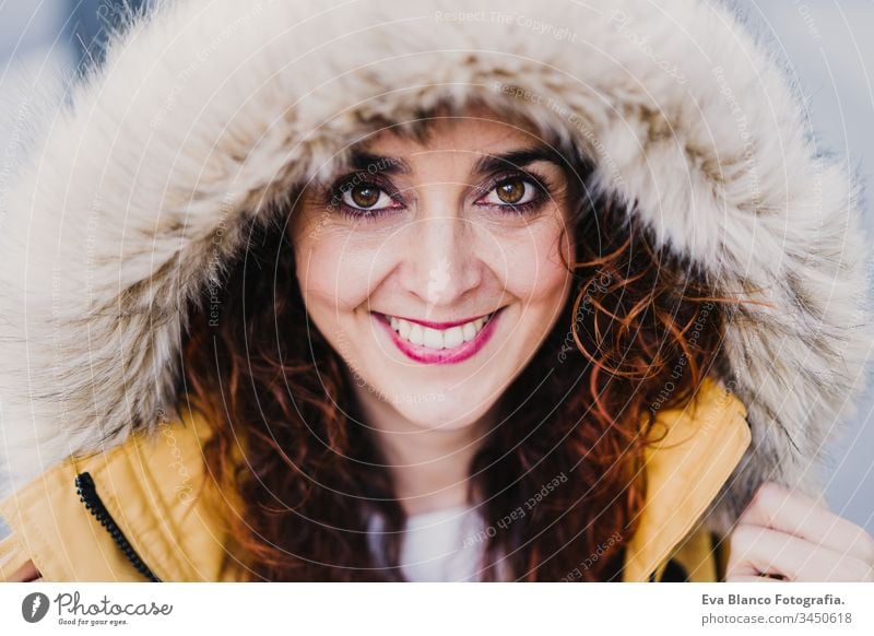 portrait of young beautiful woman wearing a hood smiling outdoors. Happiness and lifestyle yellow coat happiness city urban street smile happy caucasian adult