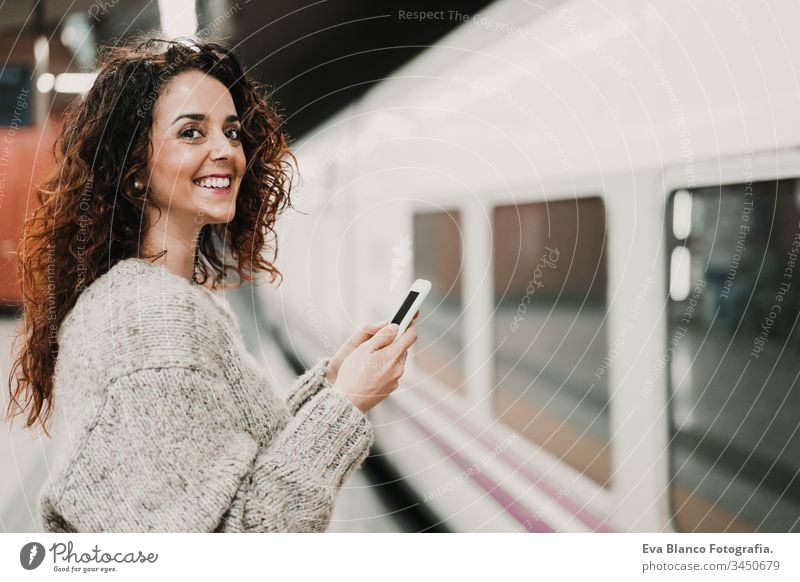 young beautiful woman at train station using mobile phone before catching a train. Travel, technology and lifestyle concept travel moving caucasian madrid