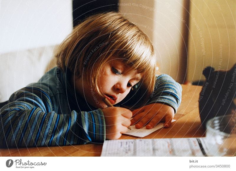 Little girl sits at home at the table in the sun and paints and learns to write for school. Flat (apartment) Stay at home inside Moody Emotions Small youthful