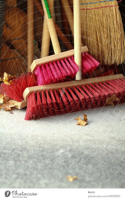 Broom with red bristles and sweeper with straw bristles, stand after work done, tidy in the garage, summer house, broom closet. Work and employment Cleaning