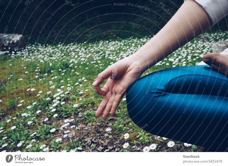 Young woman is sitting in lotus pose, outdoors in spring time with daisies yoga young nature meditation daisy healthy background exercise green grasses position