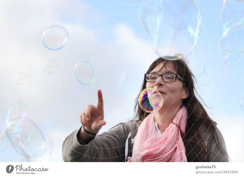 Happy young woman playing with soap bubbles Woman Young woman Colour photo Exterior shot Day Blue sky smile Good mood Joy Happiness Childhood memory