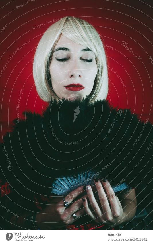 Vintage style portrait of a blonde woman covering by a hand fan mysteryous cabaret theatre custom actress vintage retro circus red black middle age dark