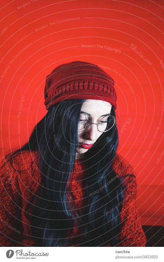 Portrait of a young brunette woman agains a red background portrait studio nerd nerdy glasses pretty face different cool black mood moody expression emotion