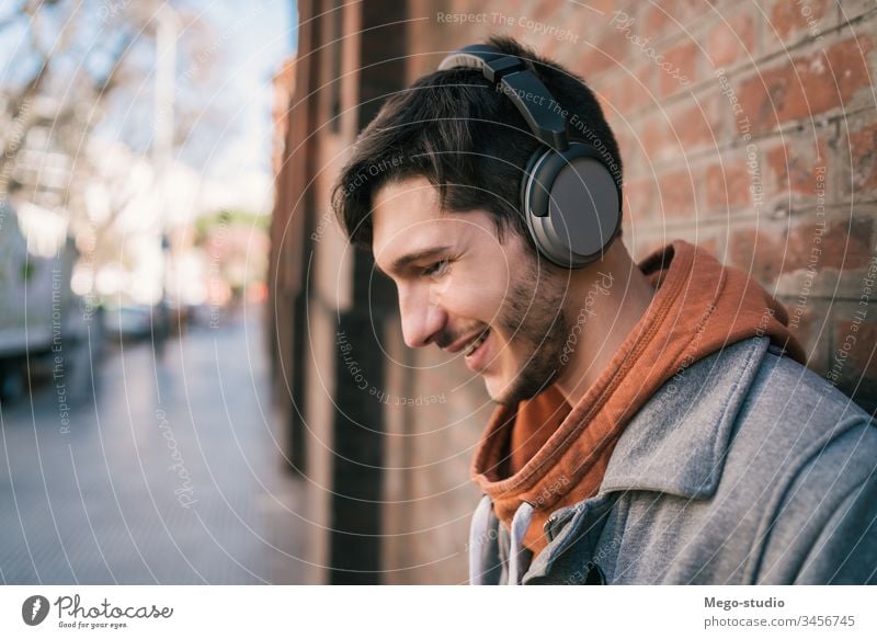 Latin man listening to music with earphones. person young people adult gadget outdoor technology lifestyle male casual alone sound entertainment city enjoying