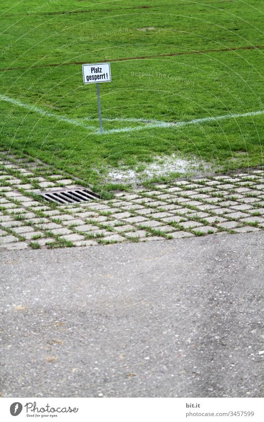 Square closed, written on sign in the corner of a sports field with green grass, next to a street. Places Place closed Barred Closed Sports Word