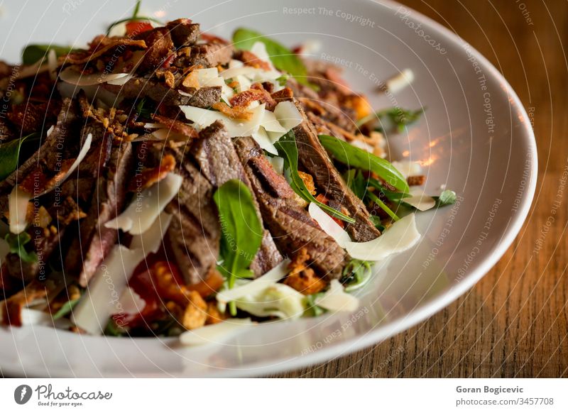 Beefsteak salad with lettuce, rocket,  and spinach with parmesan and 
homemade spicy croutons plate vegetable beefsteak restaurant meal grilled meat dinner food