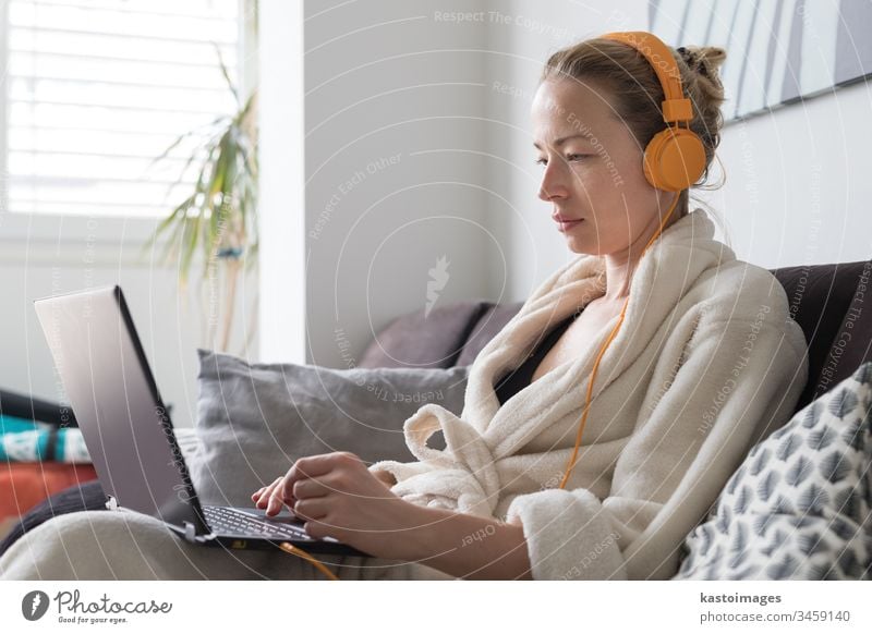Stay at home and social distancing. Woman in her casual home bathrobe working remotly from her living room. Video chatting using social media with friend, family, business clients or partners.