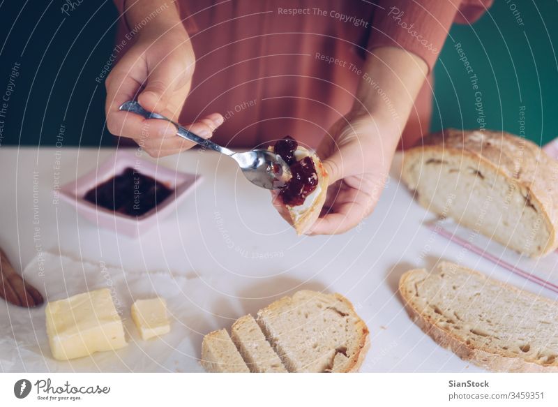 Womans hand spreads jam on homemade bread making kitchen green background dress marble toasted spoon table calories eating young protein jar peanut jelly