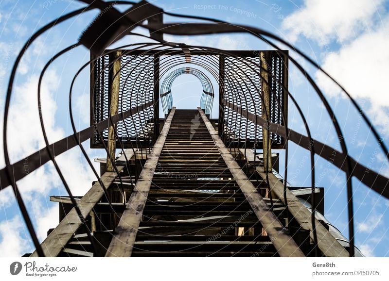 old rusty staircase with damages against the blue sky and clouds climb gray grunge industrial iron iron staircase ladder line lines metal overlap perspective