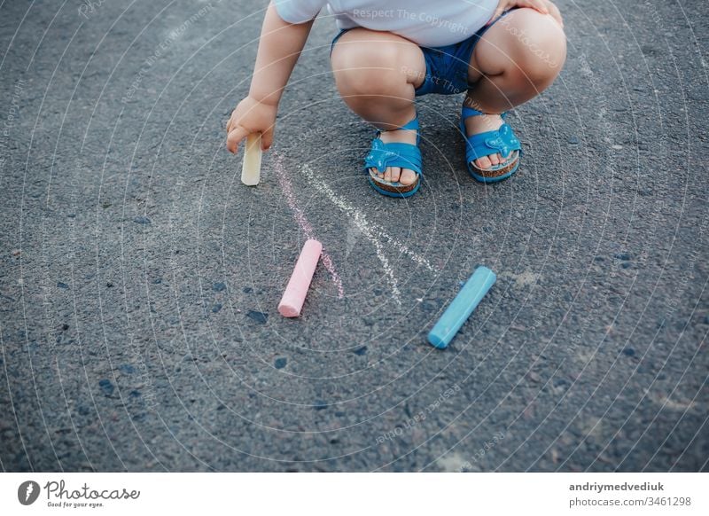 Close up of little girl drawing with chalks on the sidewalk color hand pavement art summer background colorful fun outdoor child park leisure small kid play