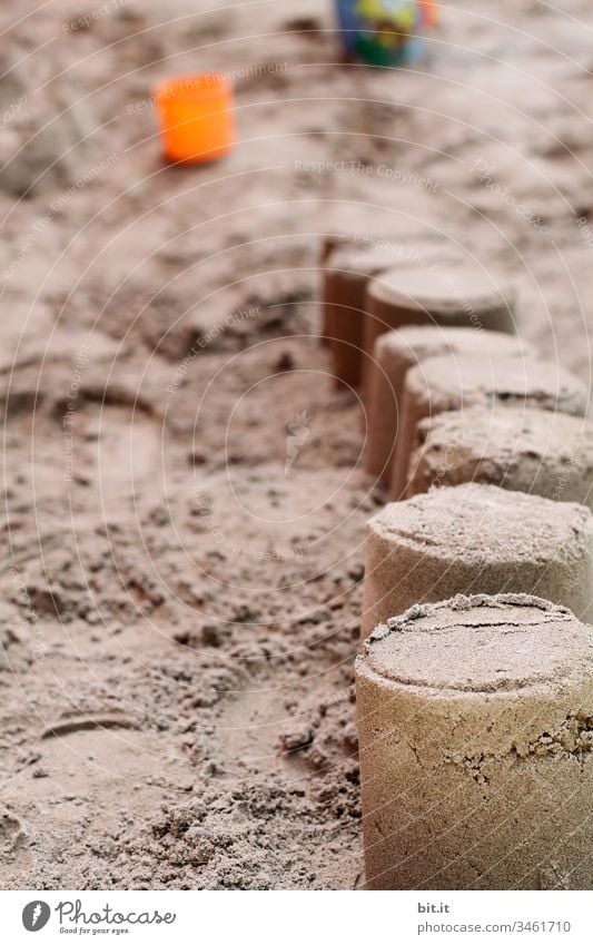 Sand cake or sand castle built with sand on the beach or in a sandbox, on holiday, with bucket and sand moulds in the background. Beach Coast Playing