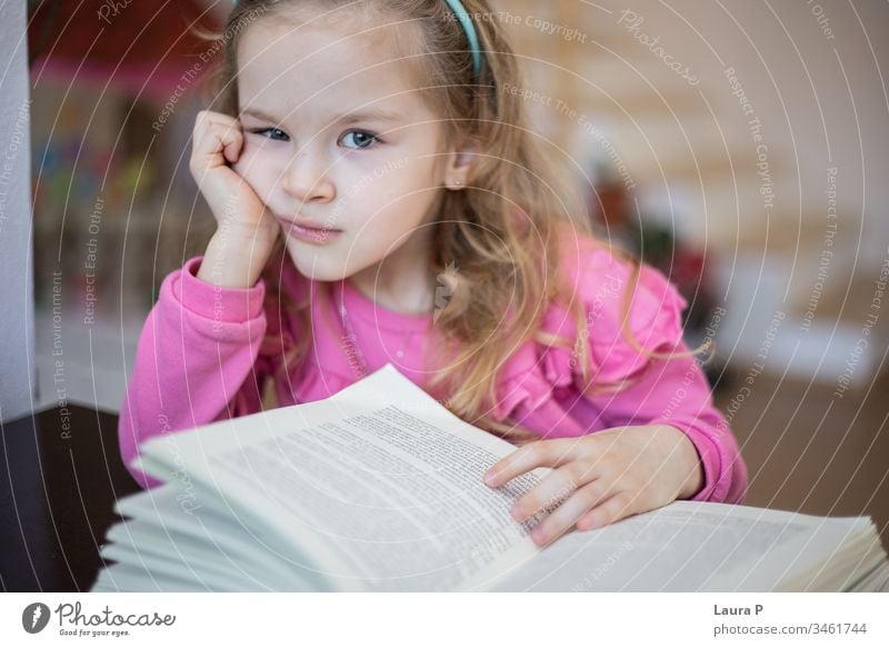 Little blonde girl tired and bored of reading and doing homework adorable attentive attentively beautiful book caucasian child childhood clever closeup
