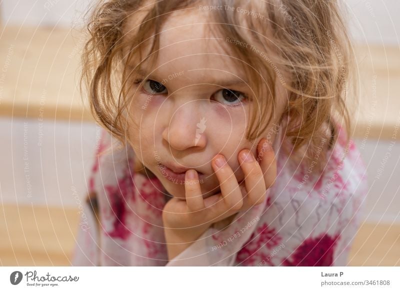 Close up of an upset little blonde girl holding her chin in her hand adorable alone angry bad mood beautiful bored child childhood cute emotion emotional