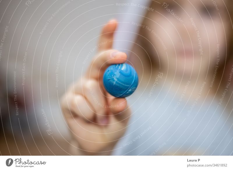 Close up of child fingers holding a small blue ball blurred background close up family time play showing pressing joy color care girl cheerful children toddler