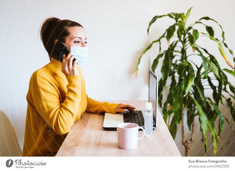young woman working on laptop at home, wearing protective mask. work from home, stay safe during coronavirus covid-2019 concpt pandemic stay home dog pet