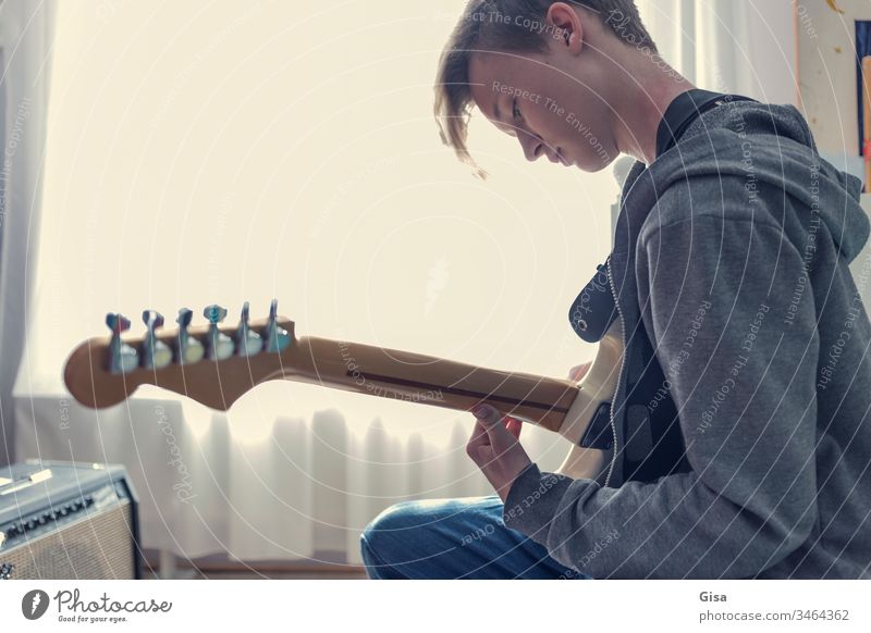 Male teenager plays an electric guitar in his room. Guitar Electric guitar Fantasy Sunlight Youth culture Window Room Quarantine covid-19 Virus Creativity